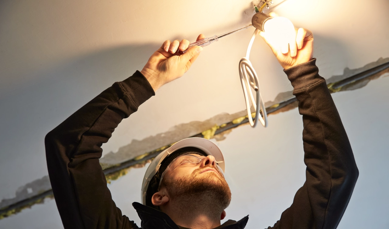 Electrician installing a light bulb on ceiling.