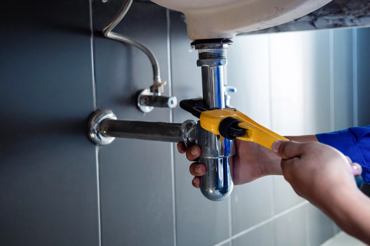 Plumber fixing sink pipe with wrench.