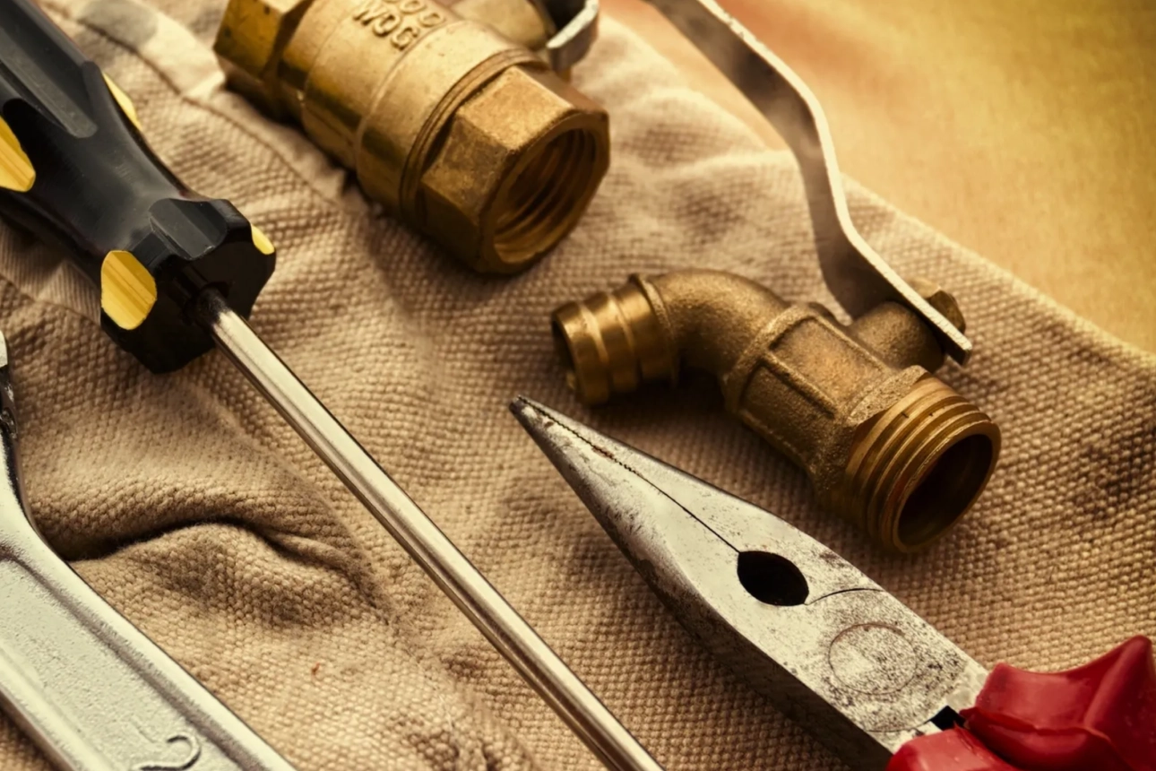 Tools and plumbing parts on fabric surface.