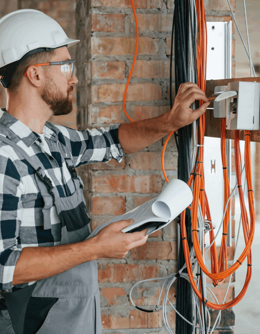 Electrician inspecting wiring with blueprint.
