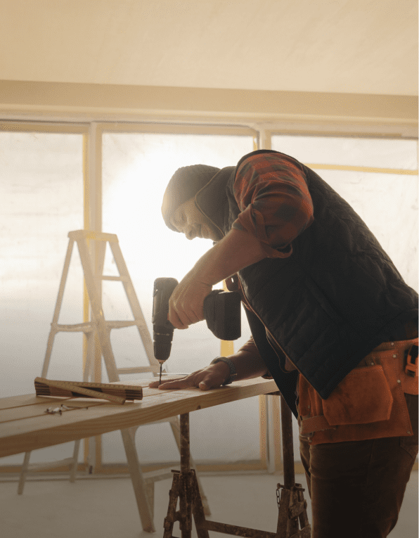 Man using drill on wooden plank indoors.