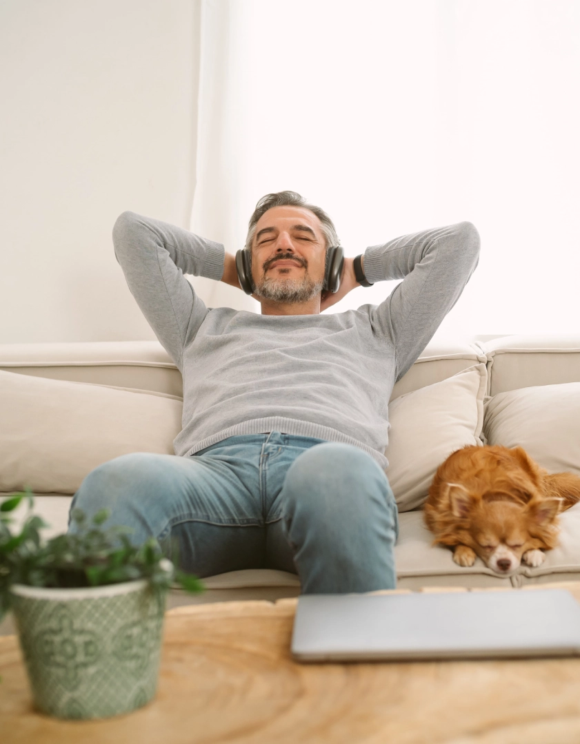 Man relaxing with headphones, dog sleeping nearby.