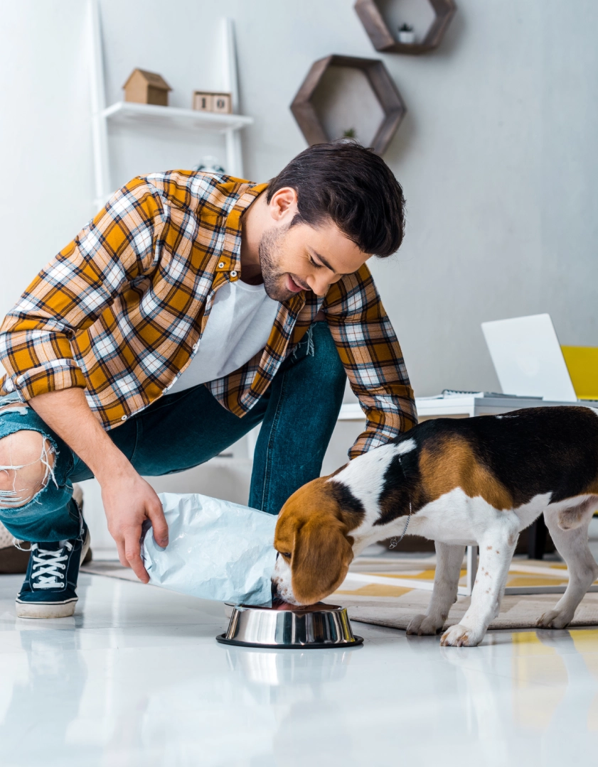 Man feeding dog from a bowl.
